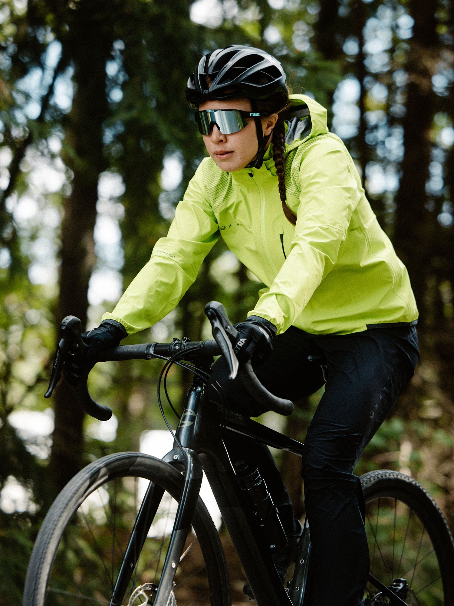 Halti Liike Naisten 3L DrymaxX urheilutakissa henkilö ajaa mustalla pyörällä metsäpolulla.