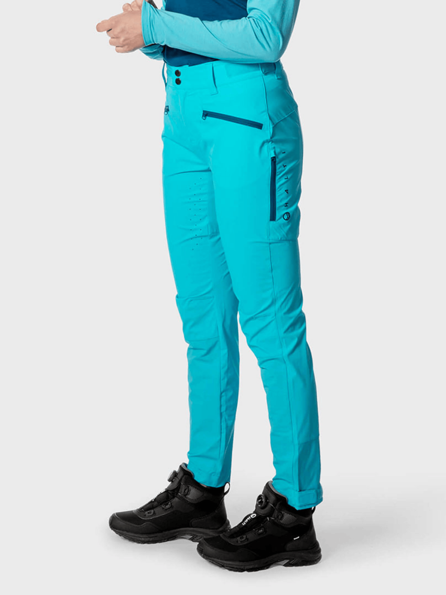 Henkilö Tracksissa Naisten X-stretch Housut by Halti ja paita, jalassa mustat saappaat – loistava aktiiviselle liikunnalle.