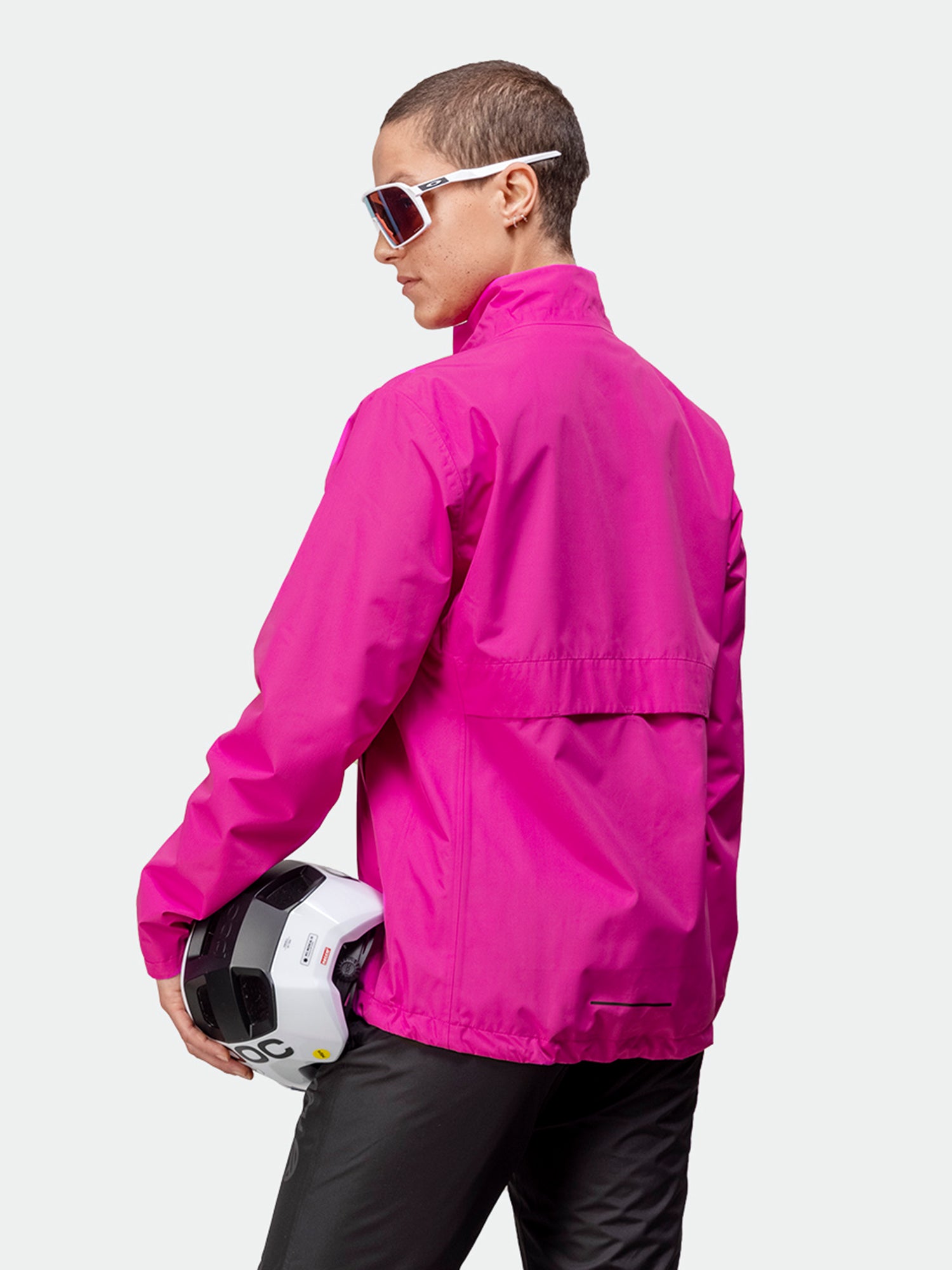 Halti Triant Pyöräilytakki Naisten takkia ja aurinkolaseja käyttävä henkilö pitelee valkoista kypärää ja katsoo poispäin kamerasta.