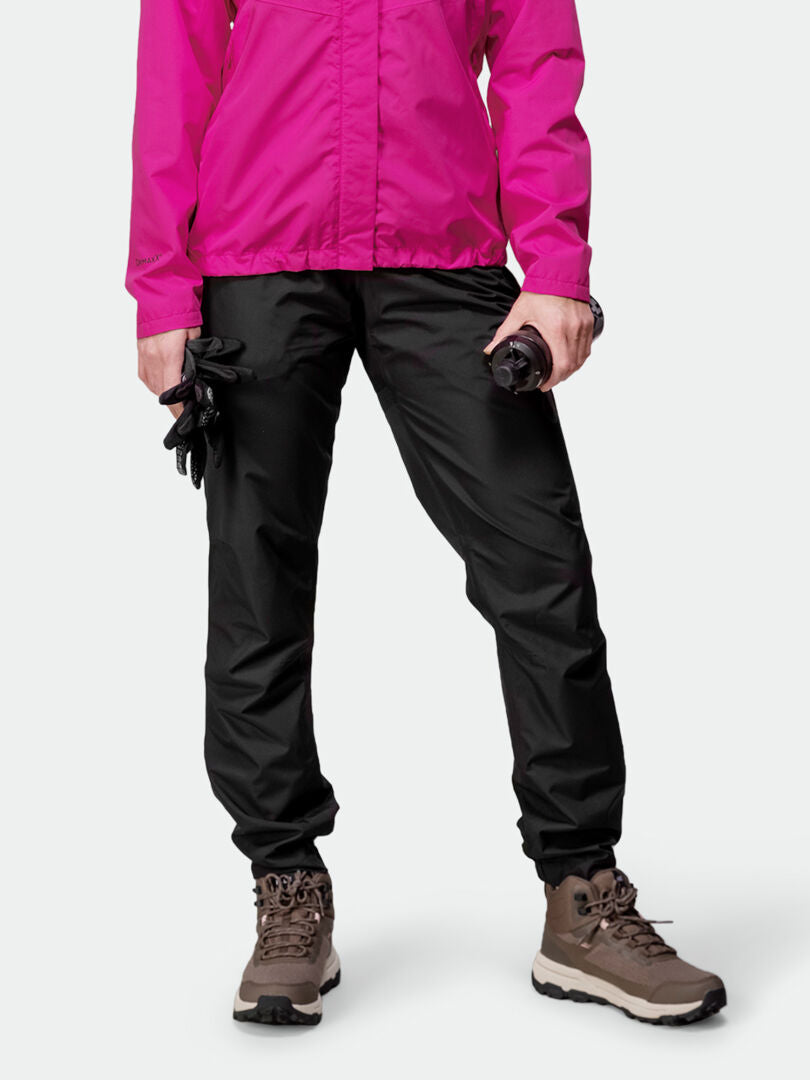 Henkilö vaaleanpunaisessa takissa, Halti Triant DX Pyöräilyhousut Naisten, ruskeissa vaelluskengissä, hansikkaiden ja juomapullon kanssa.