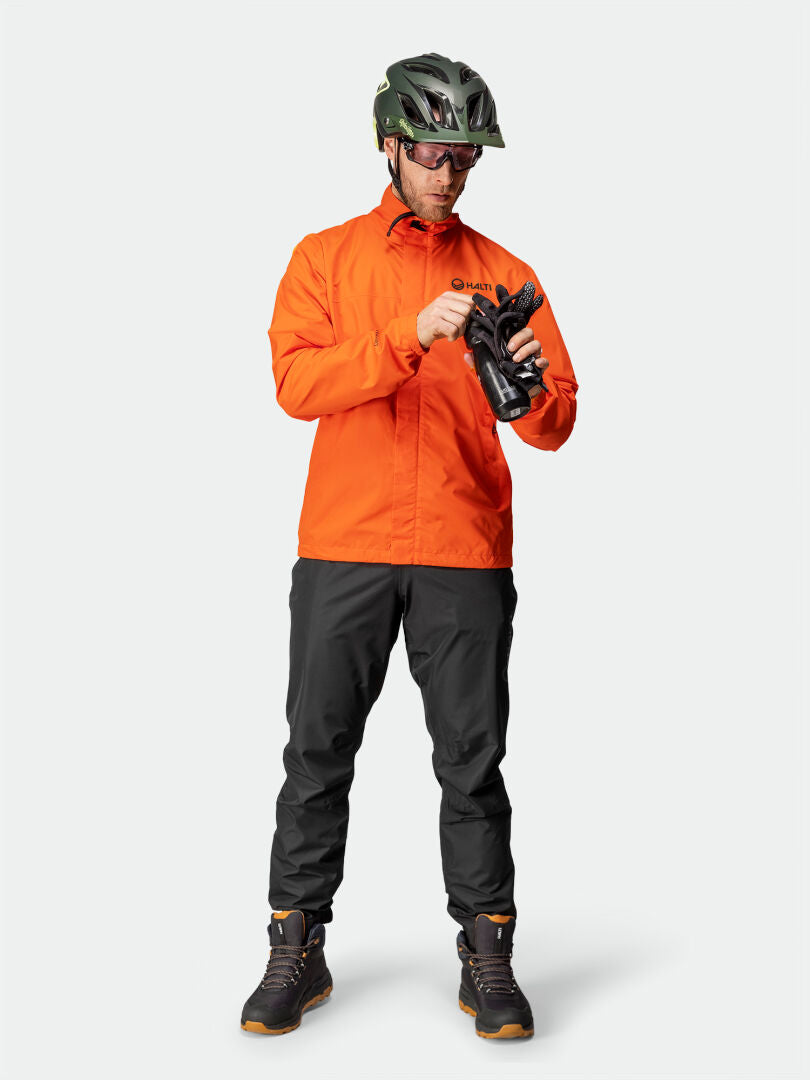 Mies Halti Triant DX Pyöräilytakki Miesten seisoo kädessään mustat hanskat ja katsoo alas.