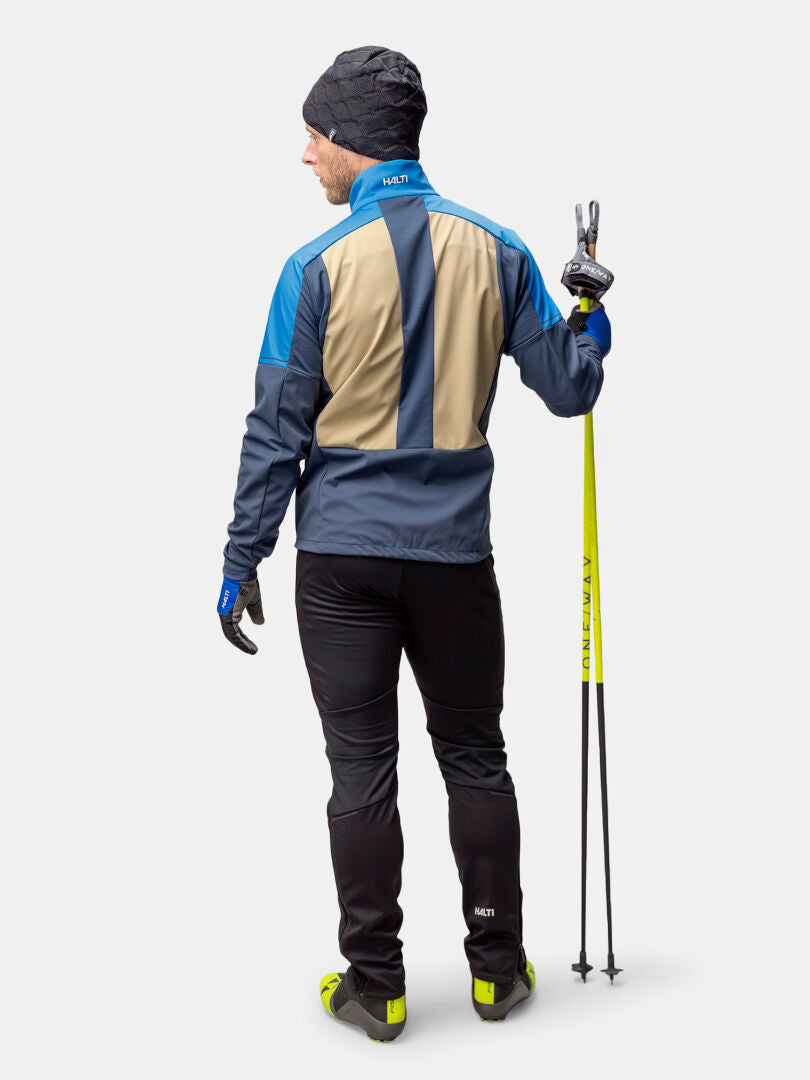 Halti Framover Hiihtotakki Miesten mies pitelee hiihtosauvoja ja tekee rauhanmerkkiä poispäin.