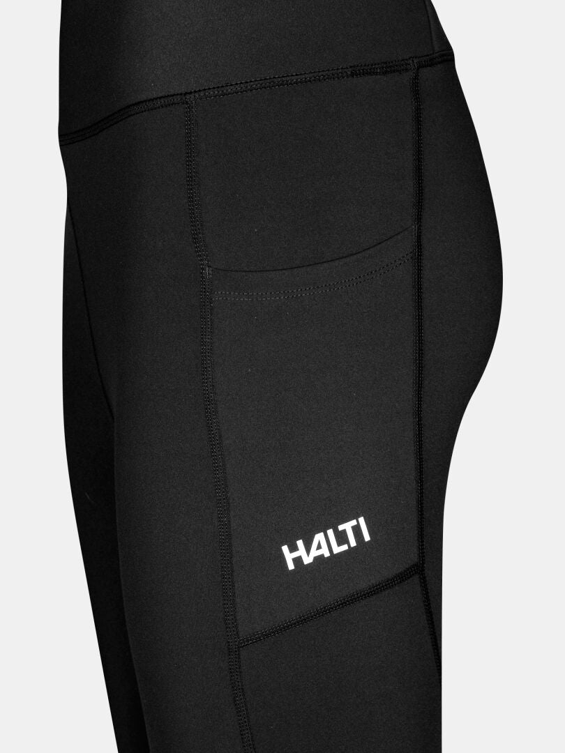 Lähikuva Halti Kaldu Treenitrikoot Naisten housuista, joissa on flatlock-saumat, sivutasku ja valkoinen Halti-logo taskussa.