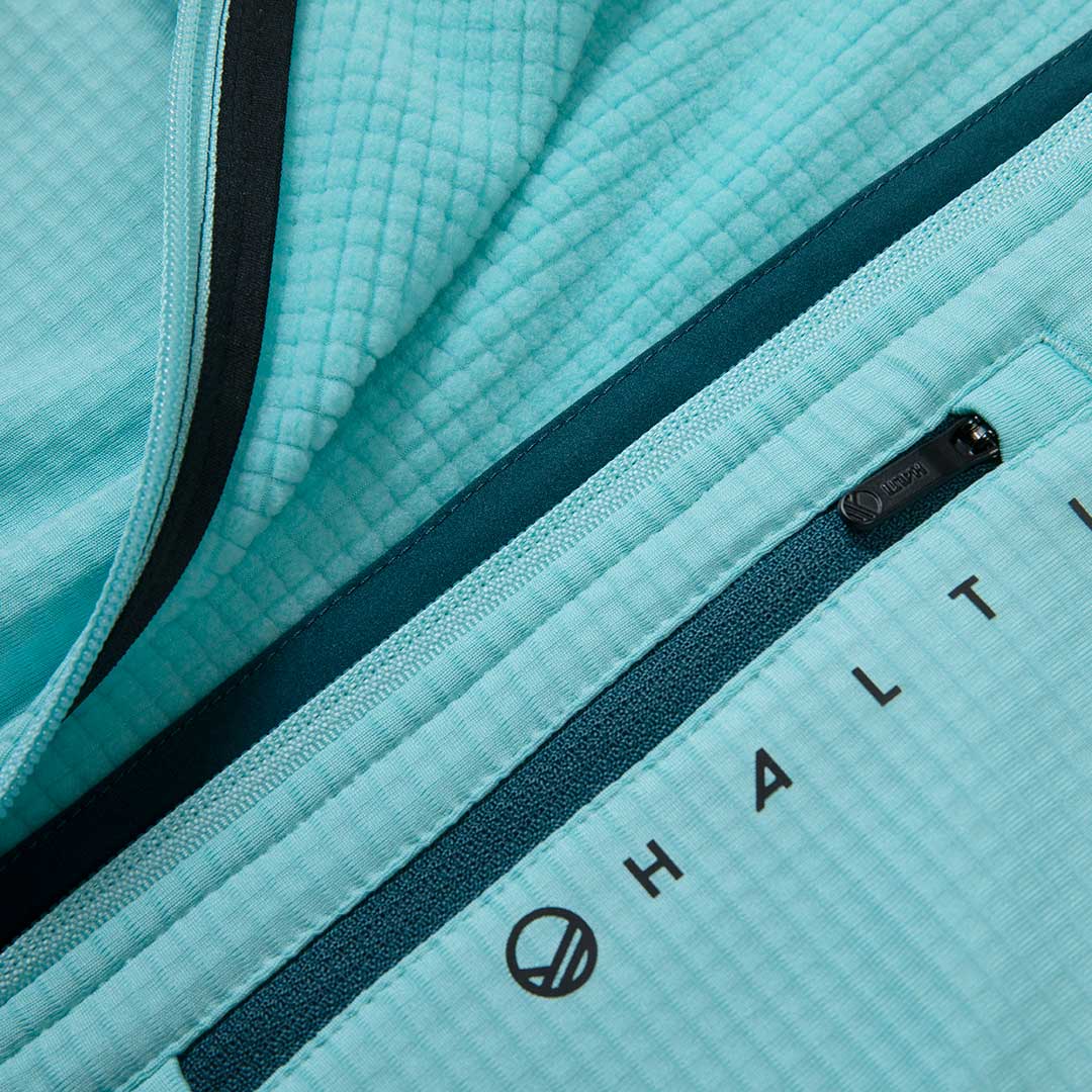 Lähikuvassa Halti Forerunner Naisten Paita, jossa on näkyvät vetoketjut ja tuotemerkit kierrätysmateriaalilla.