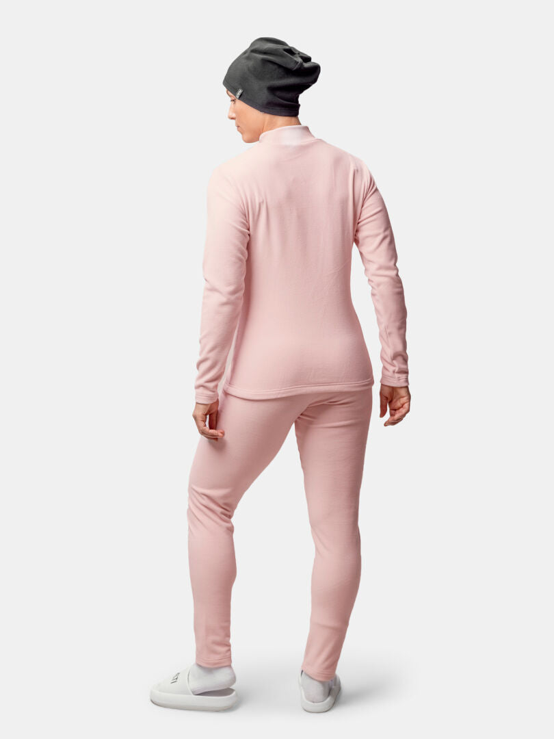 Henkilö seisoo kasvot menosuuntaan, yllään Halti Trone Fleece Paita Naisten, yhteensopivat housut, harmaa pipo ja valkoiset kengät.