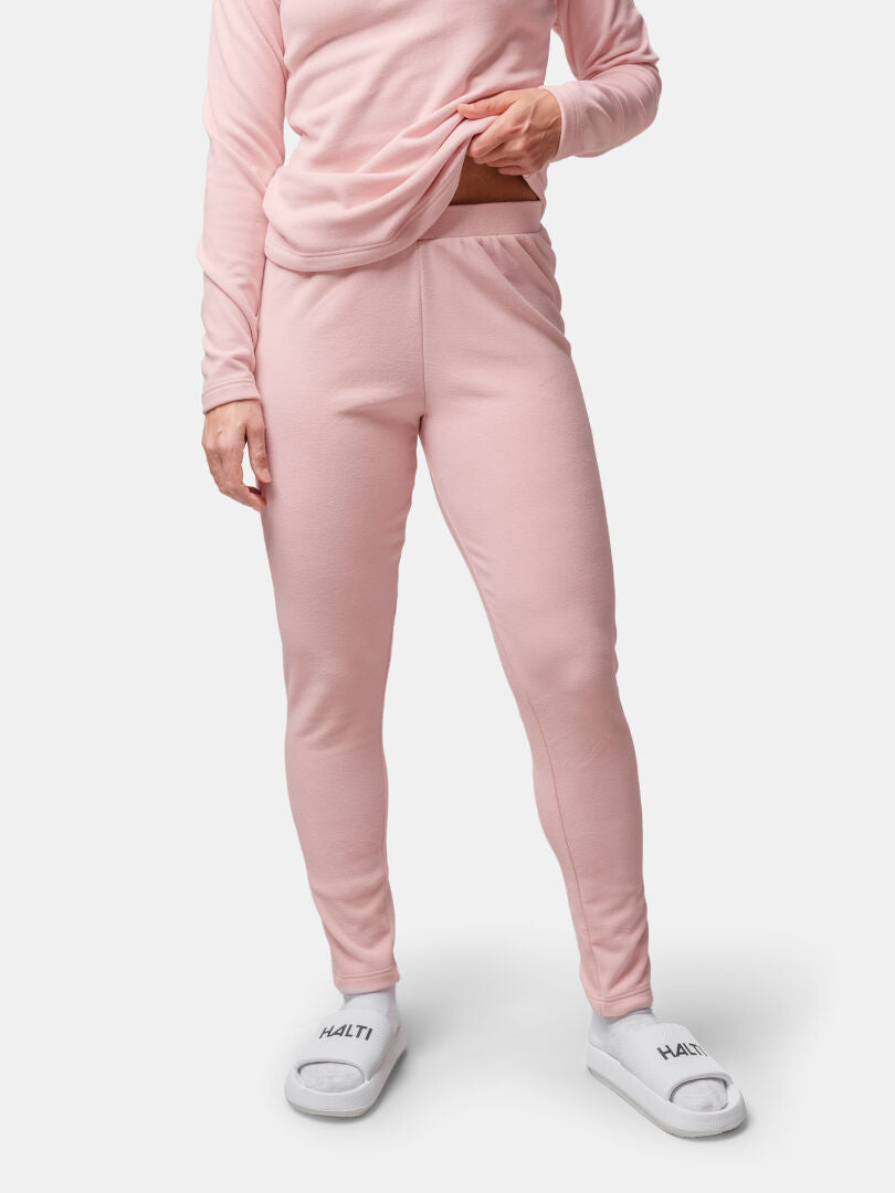 Henkilö, jolla on Halti Trone Fleece Housut Naisten vaaleanpunainen ja valkoiset tossut, seisoo tavallisella pohjalla.