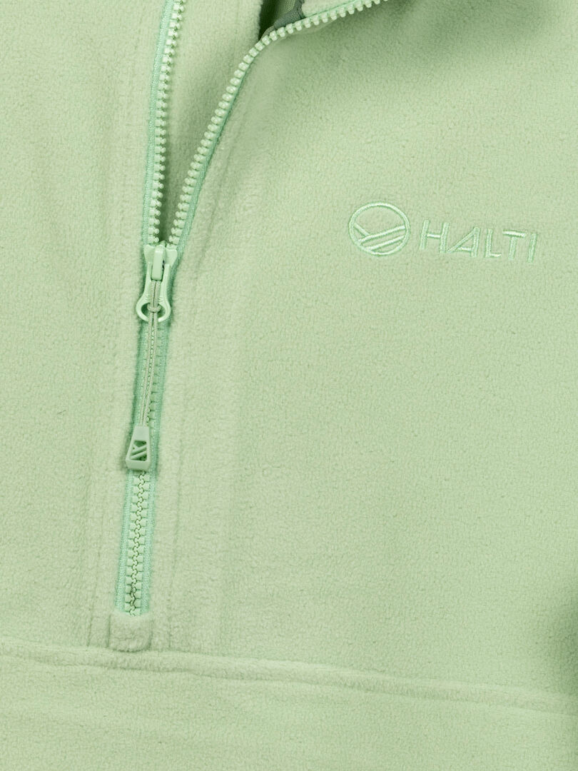 Lähikuva Halti Ossia Fleecepaita Naisten paidasta, vaaleanvihreä, jossa puolivetoketju ja Haltin logo rinnassa.