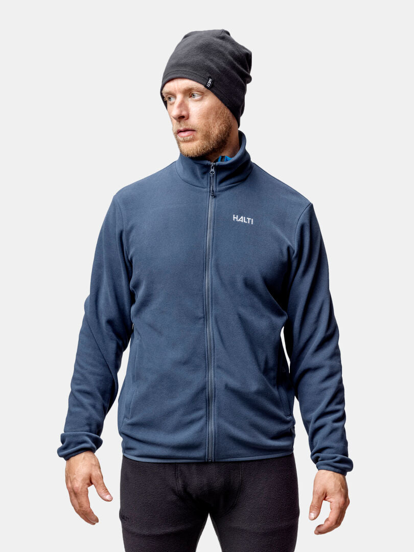 Halti Rockmoon Fleecetakki Miesten ja tummaa pipoa käyttävä mies seisoo valkoista taustaa vasten sivulle katsoen.