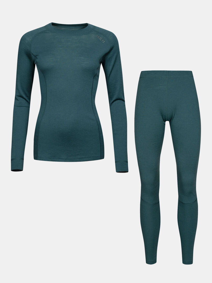 Halti Hossa II Merino Kerrasto Naisten: teal-värinen pitkähihainen paita ja leggingsit, kuvattu yksivärisellä taustalla.