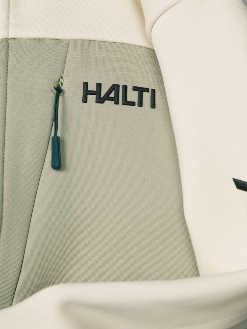 Lähikuva kaksivärisestä Halti Seiland Välitakki Naisten -fleece-takista, jossa on vetoketjullinen rintatasku ja tuotemerkin logo.