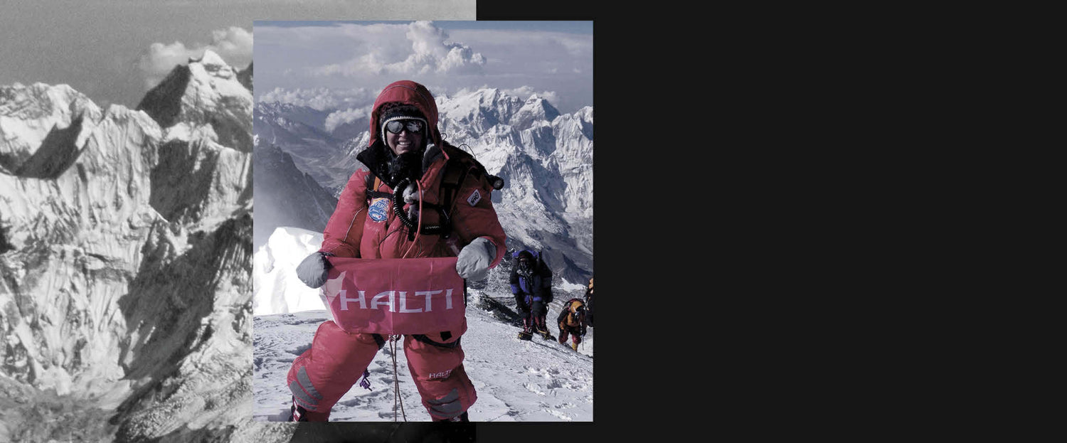 Punaisiin kylmävarusteisiin pukeutunut kiipeilijä pitelee Haltin kylttiä lumisella vuorella, kun muut kiipeilevät hänen takanaan.