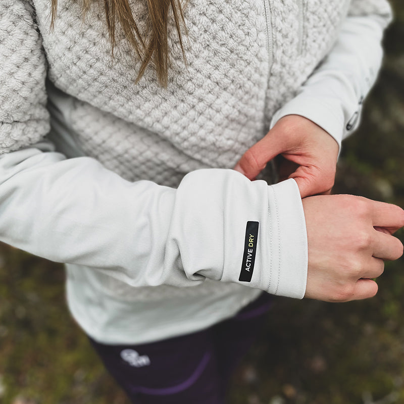 Henkilö ulkona seisomassa Haltin Forceful Naisten Välitakki -fleecetakissa, jossa on ACTIVE DRY -ominaisuus.