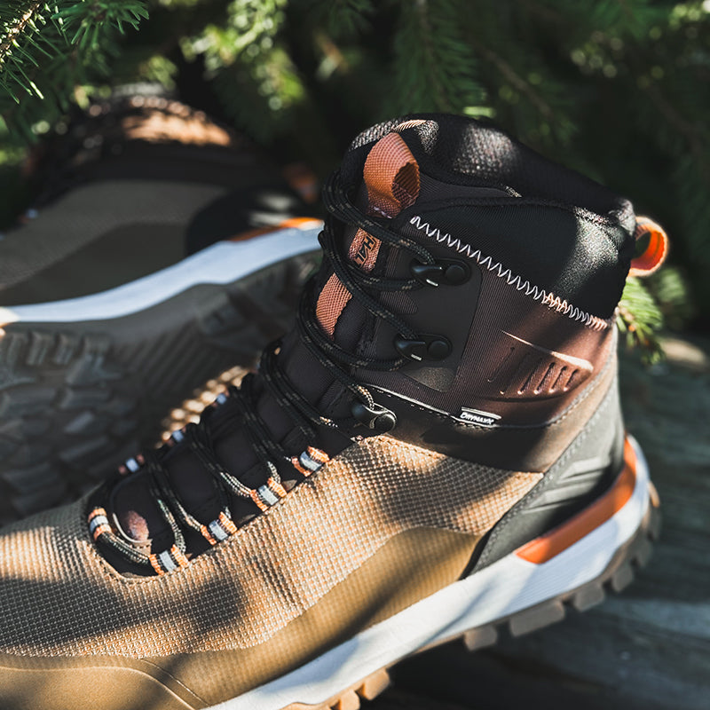 Lähikuva Halti Kajava DrymaxX Ulkoilukenkä Naisten oranssinvärisistä korosteista ja jämäkästä pohjasta, ulkona lähellä vihreitä lehtiä.