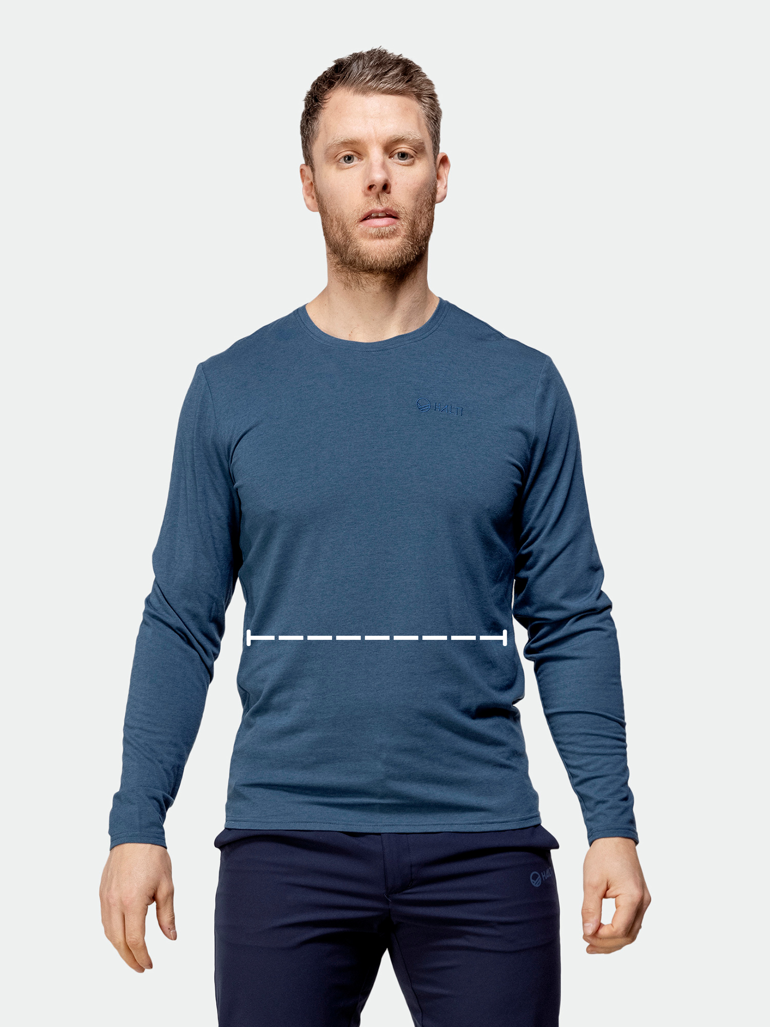 Mies, jolla on sininen pitkähihainen paita ja tummat housut, seisoo kädet hieman ojennettuina, katkoviiva keskivartalon poikki.