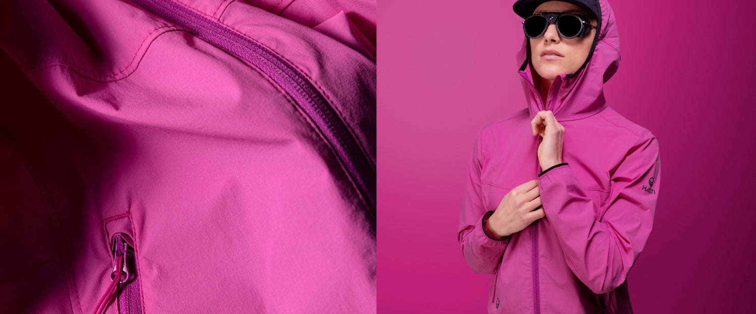 Lähikuva vaaleanpunaisen takin vetoketjusta vasemmalla; oikealla henkilö, jolla on sama vaaleanpunainen takki ja aurinkolasit.