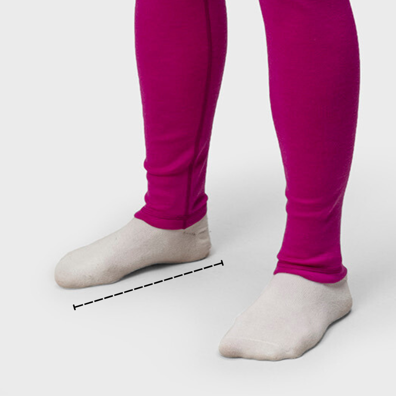 Henkilö, jolla on kirkkaan vaaleanpunaiset säärystimet ja valkoiset sukat, seisoo jalat hartioiden leveydellä toisistaan tavallisella taustalla.