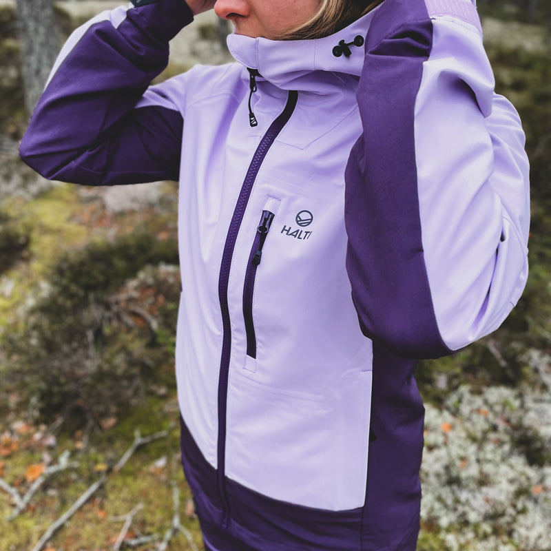 Henkilö säätää ulkona Halti Pallas III Naisten Warm Hybriditakin DrymaxX®-materiaalista valmistetun hupun ääriviivoja.