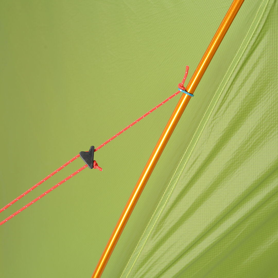 Lähikuva punaisesta vaijerista oranssissa Haltin Domino 3 Hengen Teltta -tangossa vihreää vedenpitävää kangasta vasten.