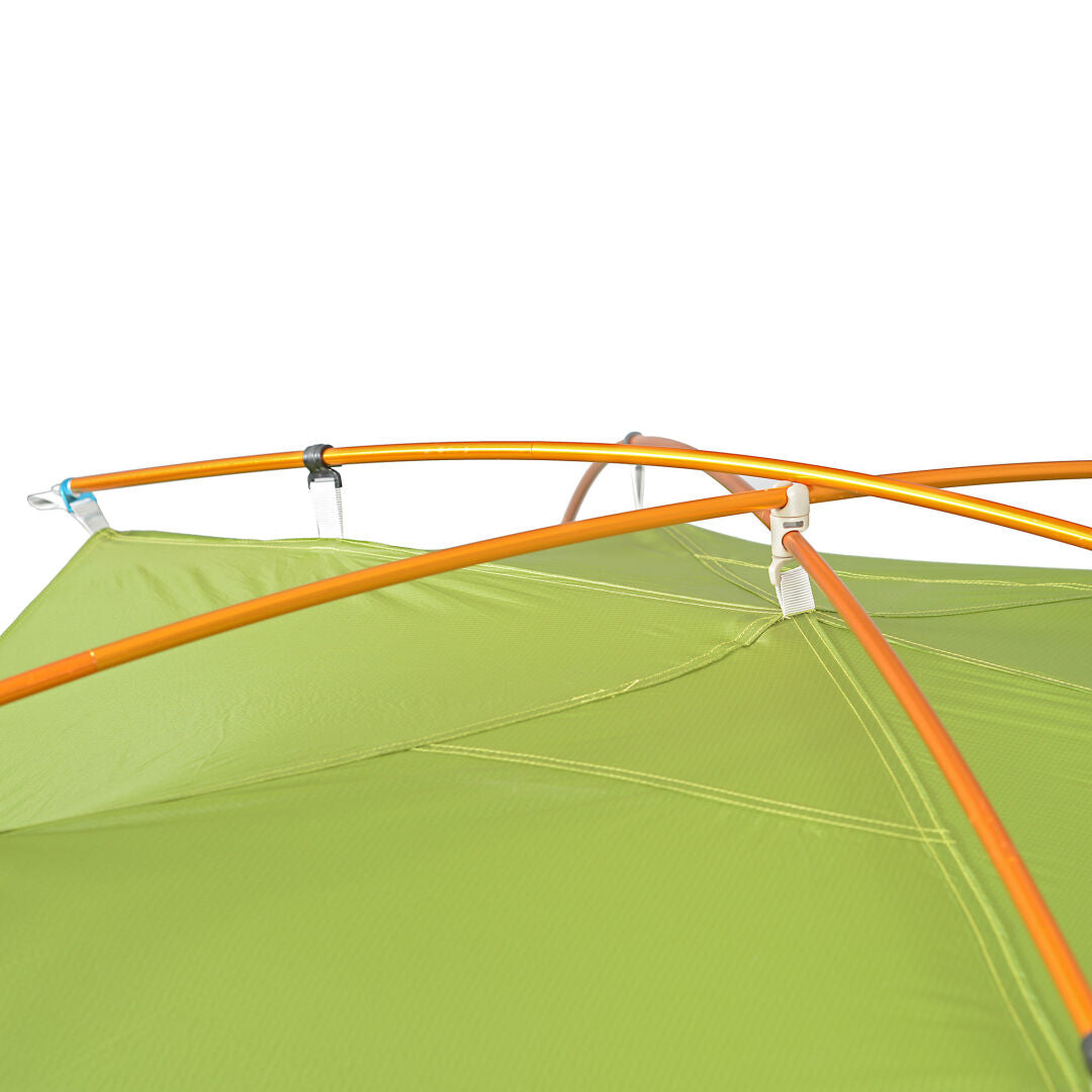 Lähikuva oransseista tolpista vihreällä Halti Domino 3 Hengen Teltta -teltalla valkoista taustaa vasten.