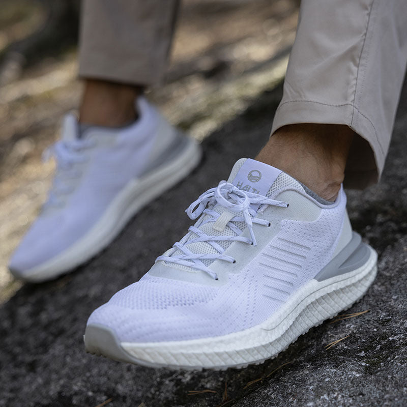 Henkilö, jolla on yllään vaaleanharmaat Halti Gale Lenkkari Miesten -kengät, joissa on BoomaxX-välipohja ja khakinväriset housut, teksturoidulla ulkopinnalla.