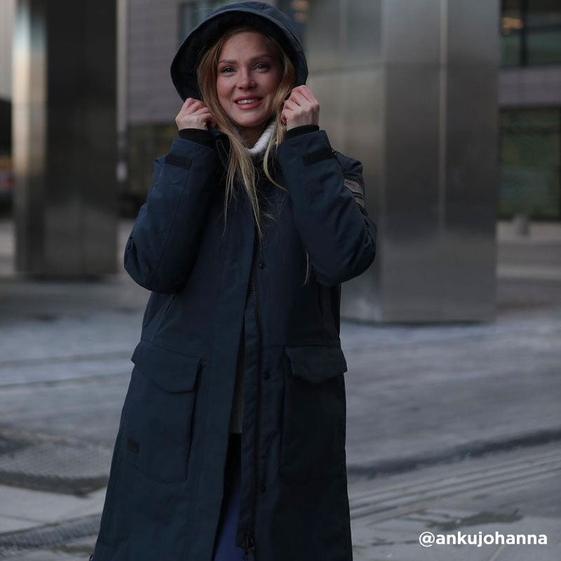 Mies Halti Bergga Naisten DrymaxX Talvitakki seisoo kaupungin kadulla ja huokuu minimalistista eleganssia.