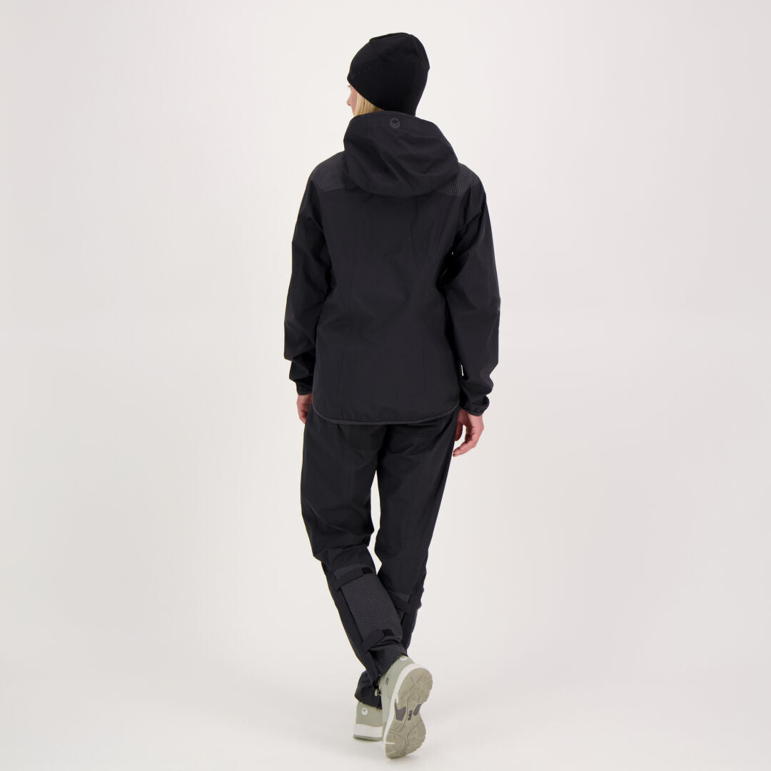 Henkilö seisoo selkä kameraan päin mustissa Halti Liike Naisten 3L DrymaxX urheiluhousuissa, mustassa pipossa ja kevyissä kengissä.