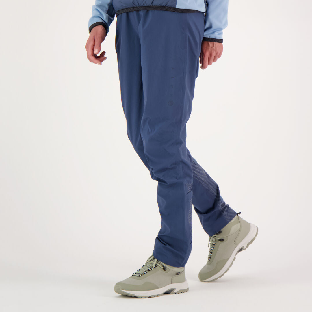 Henkilöllä on yllään Halti Liike Naisten 3L DrymaxX urheiluhousut, vaaleansininen takki ja harmaat vaelluskengät valkoisella taustalla.