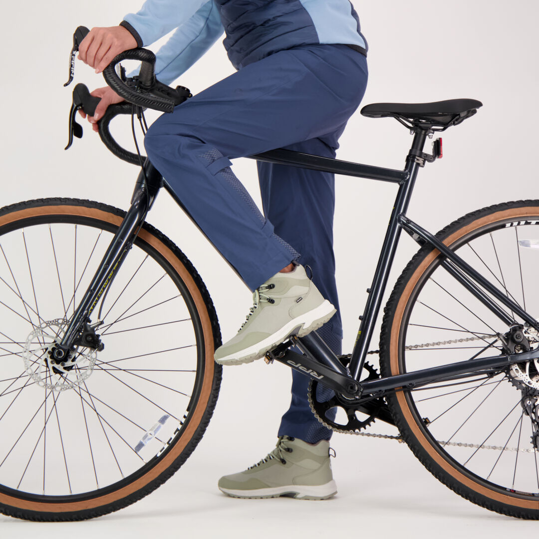 Henkilö Halti Liike Naisten 3L DrymaxX urheiluhousut ja vaaleanharmaat kengät istuu mustalla pyörällä valmiina treenaamaan.