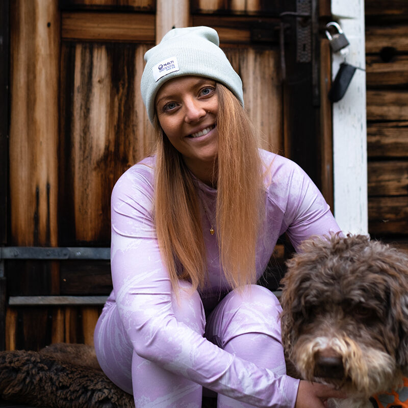 Halti Windfire Kerrasto Naisten pehmeä harjattu sisäpinta hymyilee ovella kiharakarvaisen koiransa kanssa.