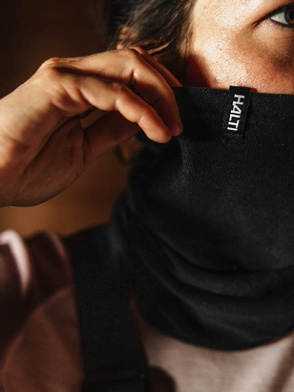 Mies, jolla on olkapäiden pituiset hiukset ja musta neuletakki, on upotettu hartioitaan myöten jäiseen veteen, lumen ja jään ympäröimänä, silmät kiinni.