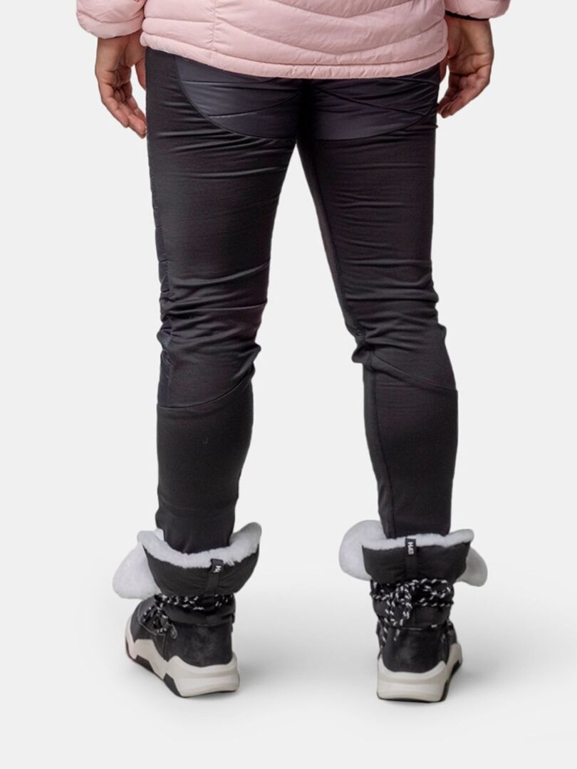 Henkilö seisoo kasvot menosuuntaan Halti Jeti DX Talvikenkä Naisten saappaat, mustat housut ja vaaleanpunainen takki.