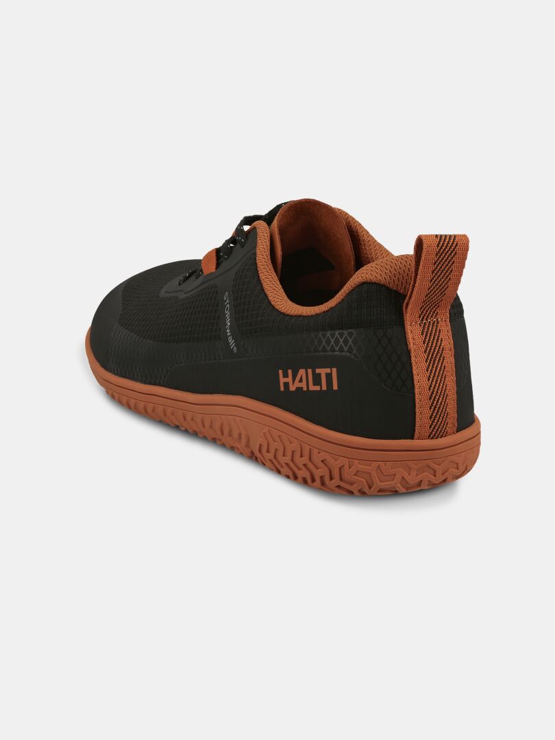 Musta ja ruskea Halti Tuntuma Paljasjalkakenkä unisex lenkkari kuvioidulla pohjalla ja vetoketjulla, selkänäkymä.