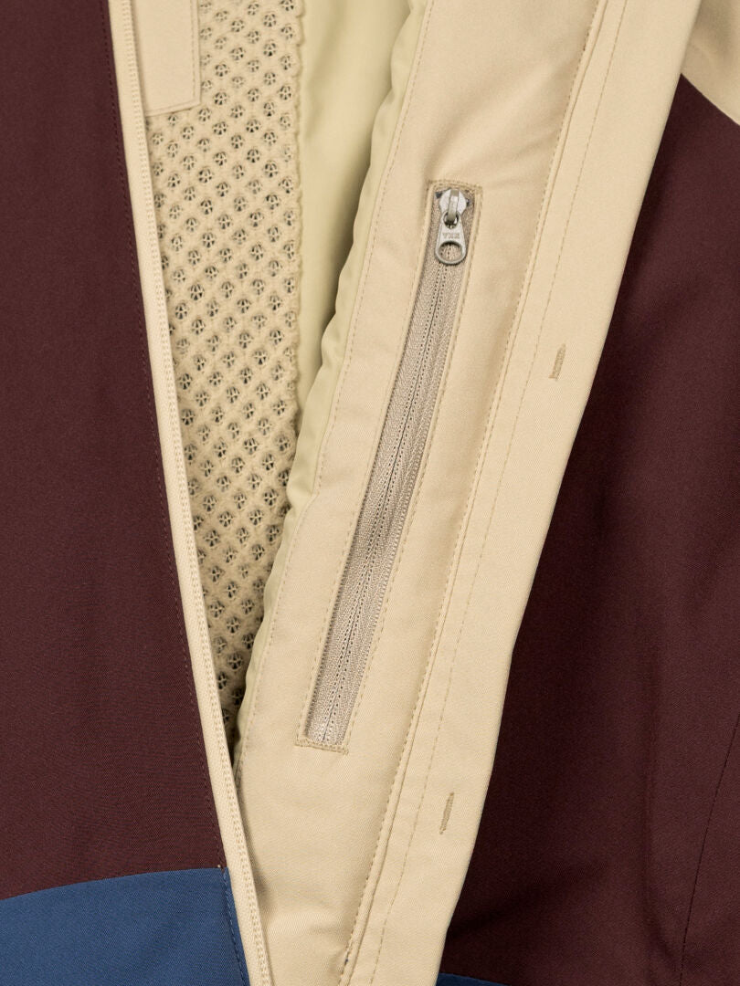 Lähikuva Halti Gracer DX Laskettelutakki Naisten, jossa on beige vetoketjullinen tasku, verkkovuori sekä beige, ruskea ja sininen lohko.