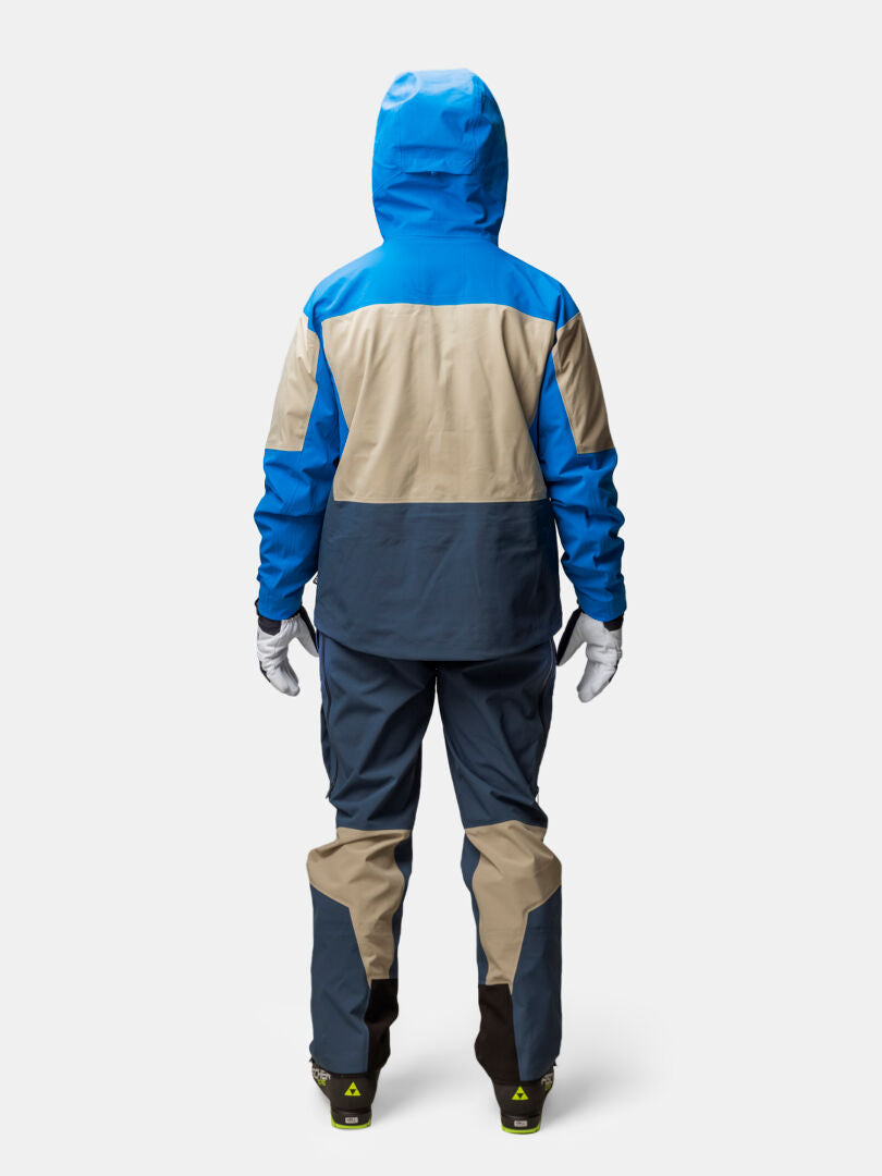 Henkilö Halti Rizle 3L DX Laskettelutakki Unisex, sininen/beige/tummanharmaa, seisoo kasvot menosuuntaan tavallisella taustalla.