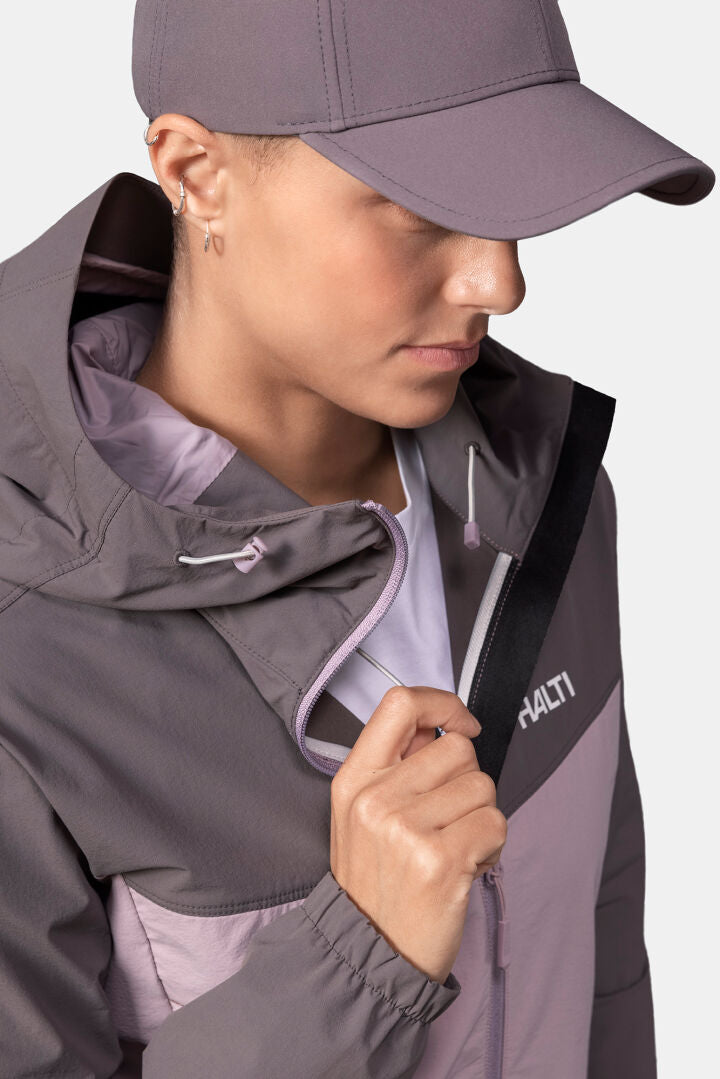 Henkilö Halti Pallas Evo X-stretch Takki Naisten takissa, pitää kiinni vetoketjun läpästä ja katsoo alaspäin.