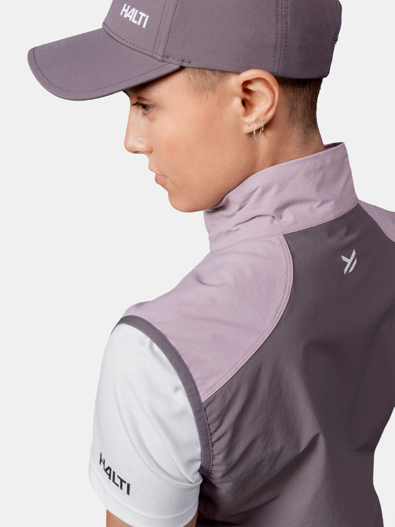 Henkilö, jolla on violetti Halti-lippis, takki ja Pallas Evo X-stretch Liivi Naisten valkoinen paita, kasvot poispäin.