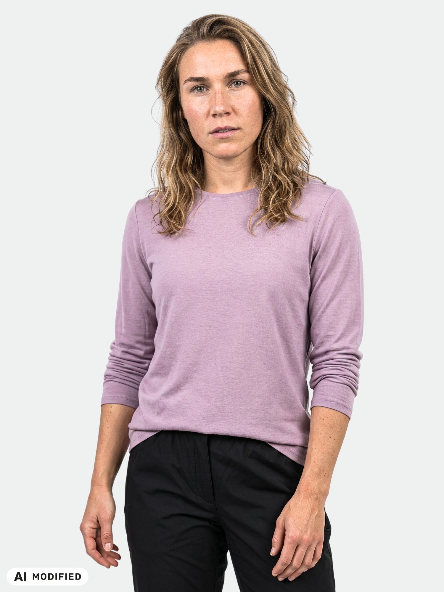 Henkilö seisoo yksivärisen taustan edessä yllään Halti Tuntu II Pitkähihainen Merino Paita Naisten ja mustat housut.