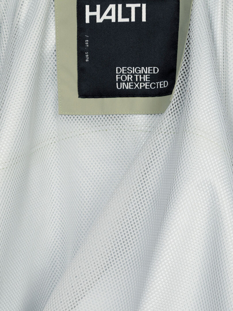 Lähikuva Halti Staala DX Kuoritakki Naisten -vaatteen etiketistä, jossa lukee ”DESIGNED FOR THE UNEXPECTED” verkkokankaalla.