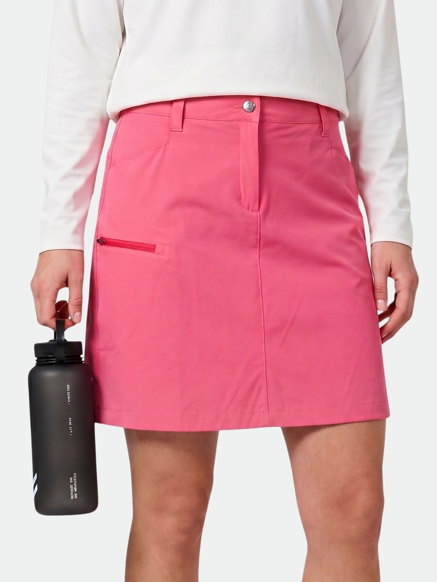 Valkoiseen paitaan ja vaaleanpunaiseen Halti Pallas Cool Shortsihame Naisten pukeutunut henkilö pitää vasemmassa kädessään mustaa vesipulloa.