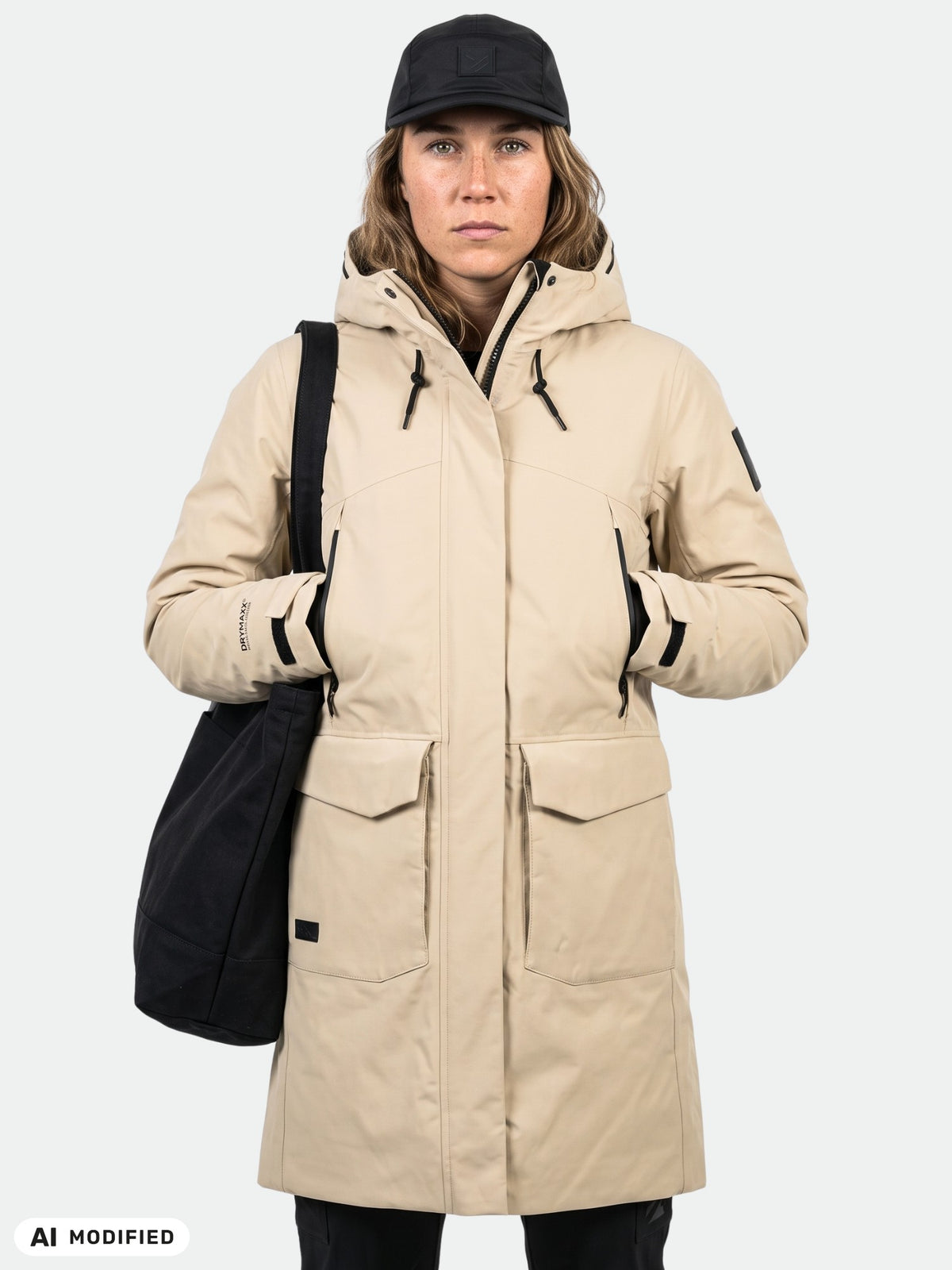 Henkilö, jolla on yllään Halti Bergga DX -talvitakki (naisten malli) heijastin yksityiskohdilla, pitää kädessään mustaa olkalaukkua.