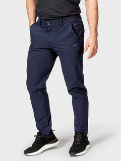 Henkilö, jolla on Halti Drive Miesten X-stretch -chinot ja musta t-paita, seisoo kädet taskuissa tavallista taustaa vasten.