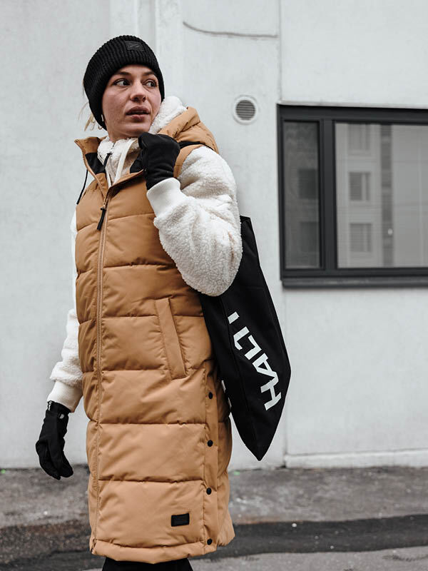 Ruskehtavaan Halti Penger Toppaliivi Naisten ja mustaan pipoon pukeutunut henkilö pitelee HALLI-kantolaukkua ulkona.
