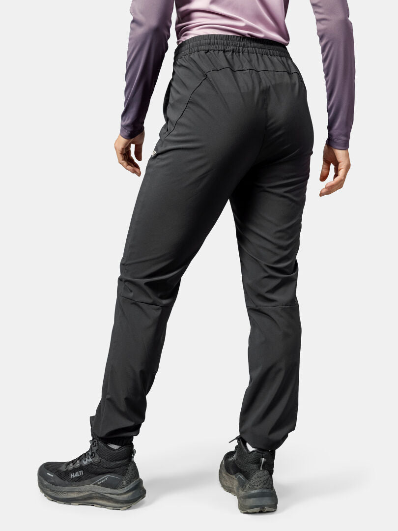 Henkilöllä on yllään mustat Halti Grets Joggersit Naisten, vaelluskengät ja pitkähihainen violetti paita, kuvattu takaa.