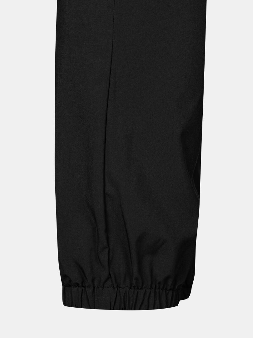 Lähikuva Halti Grets Joggersit Miesten mustista housujen lahkeista, joissa on joustava hihansuu ja Quick Dry Lite Stretch -kangas.