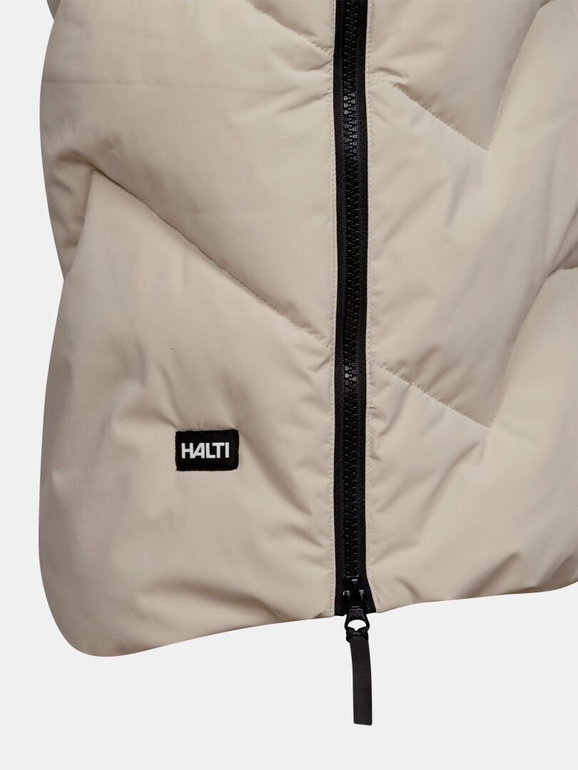 Lähikuva Halti Brahe Puffer Pitkä Talvitakki Naisten -takista, beige, mustalla vetoketjulla ja pienellä mustalla Halti-logomerkillä.