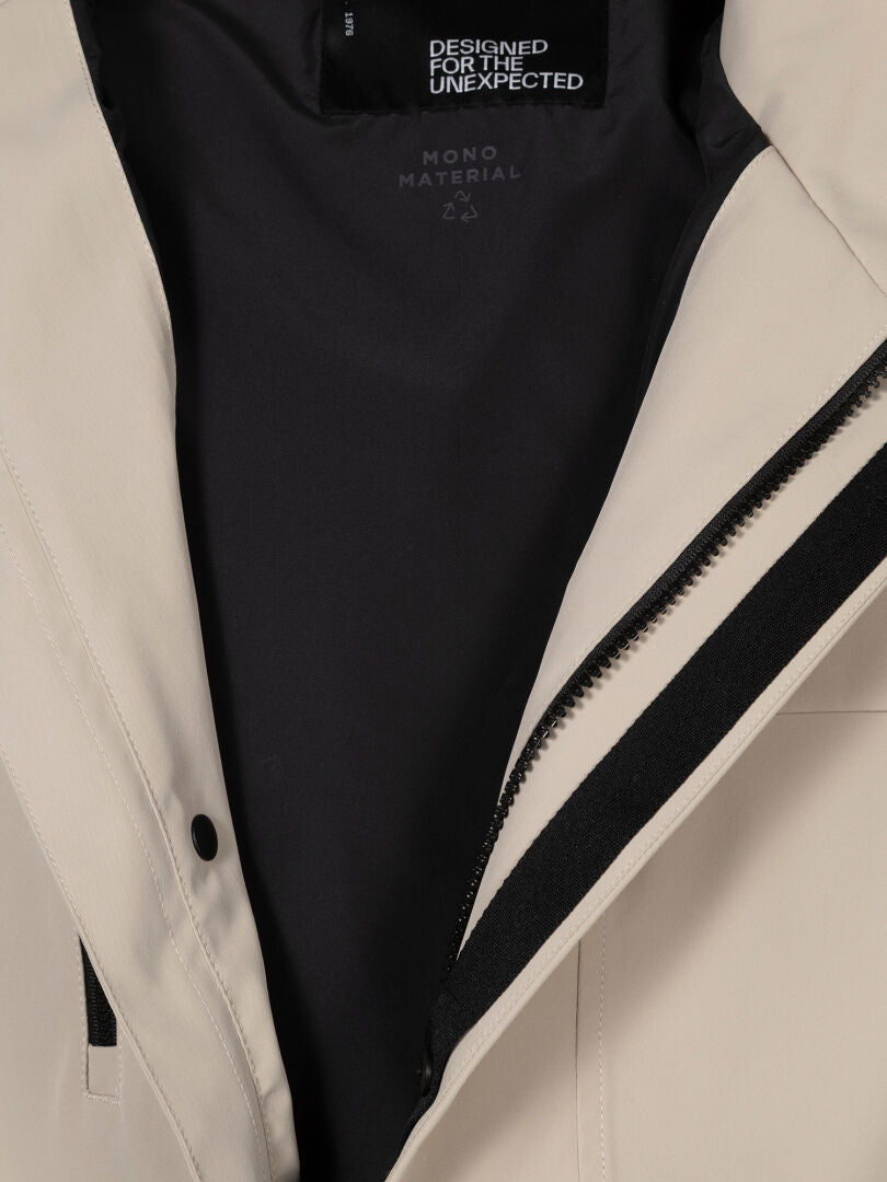 Lähikuva Halti Tokoi DX Takki Miesten avoimesta vetoketjusta, jossa näkyy musta vuori, jossa on tekstiä ja kierrätyssymboli.