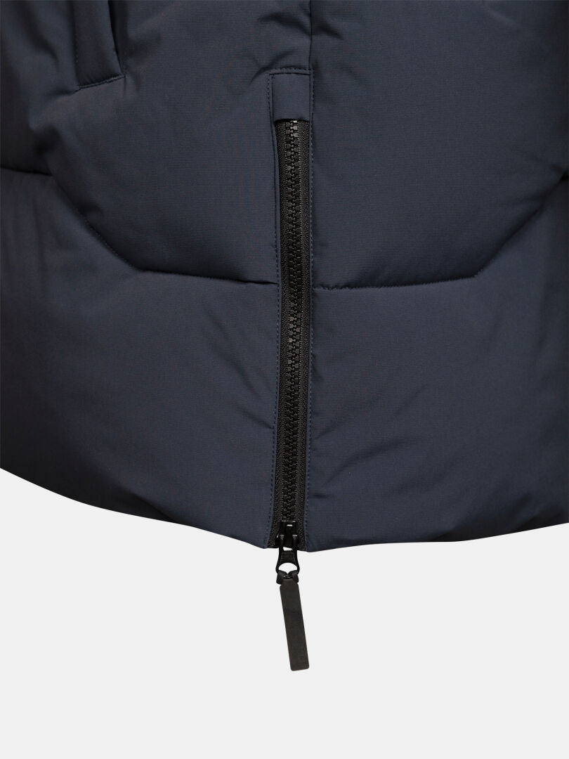 Lähikuva mustasta vetoketjusta Halti-merkin tummansinisessä Brahe Puffer Parka Miesten -takissa, tikattu kangas, valkoinen tausta.