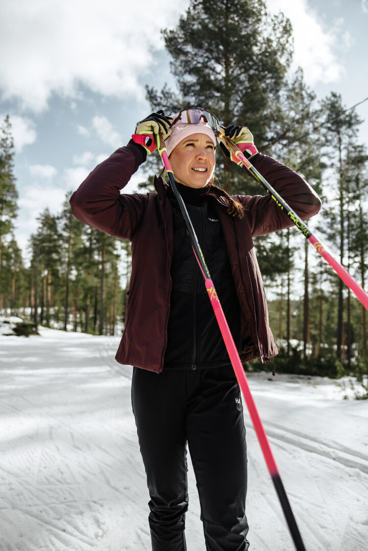 Haltian Framover Hiihtotrikoot Naisten hiihtäjä hymyilee lumisella ladulla nauttien ulkoliikunnasta metsässä.
