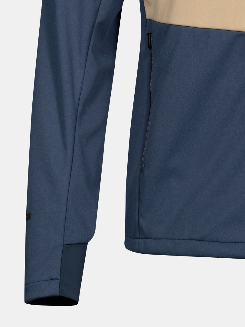 Lähikuva Halti Framover Hiihtotakki Miesten sinisellä ja beigellä värilohkoilla ja vetoketjullisella sivutaskulla.