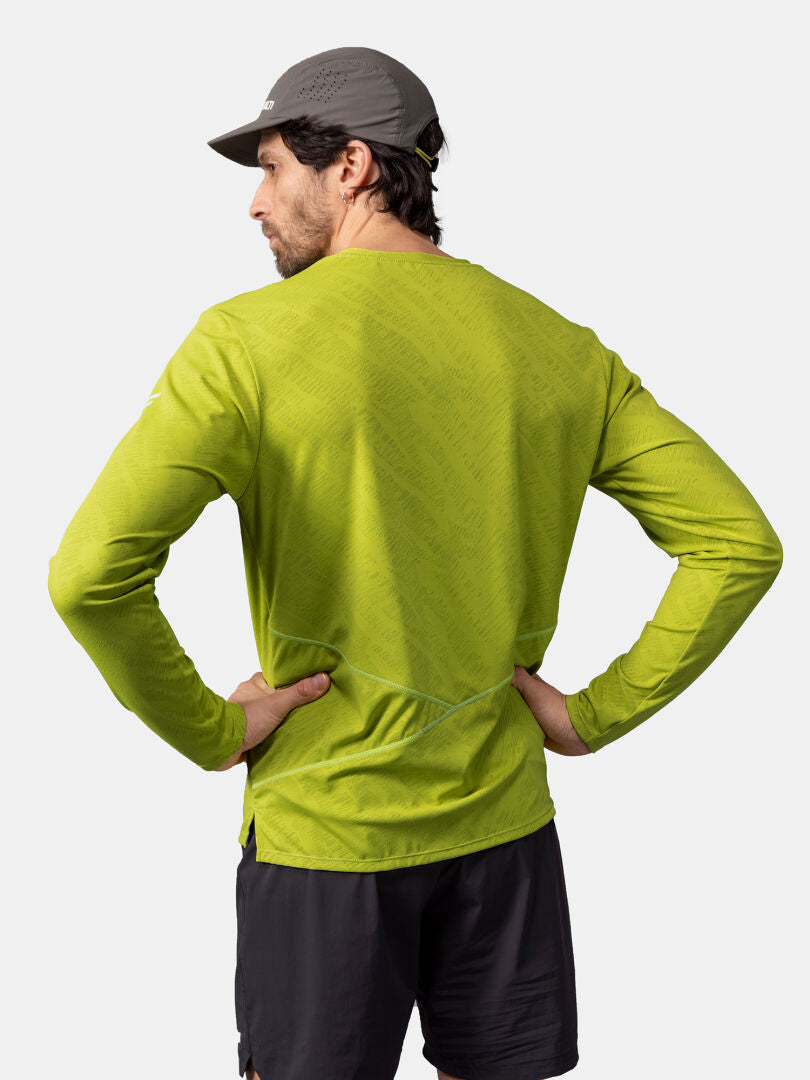 Mies, jolla on harmaa lippis ja Halti Oulanka Treenipaita Miesten seisoo kädet lanteilla, mustat shortsit jalassa, kasvot poispäin.